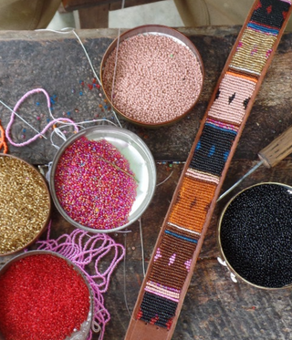 Sustainable and Ethical Practices Aspiga - pots of beads on a table creating decorated belts