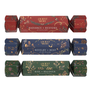 Ancient + Brave Wellness Christmas Cracker Set featuring three luxury crackers in red, blue, and green, each labeled with a wellness blend name and gold botanical illustrations.