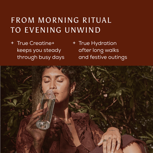A person with eyes closed drinks from a glass water bottle outdoors, supported by Rise + Recover Cracker to keep them steady through busy days and aid replenishment.
