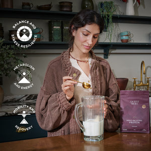 Woman preparing a protein shake with a package of Ancient + Brave's protein powder in a kitchen setting.