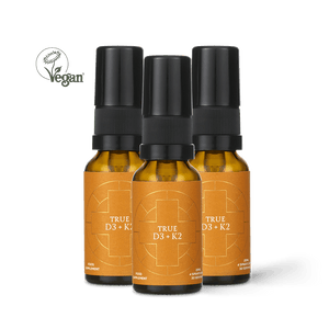 Three Ancient + Brave True Vitamin D3 + K2 bottles, featuring orange labels, are grouped together to showcase a convenient 3 Pack vitamin D3 spray for optimal bone support. A Vegan symbol with a leaf appears in the top left corner against a plain white background.