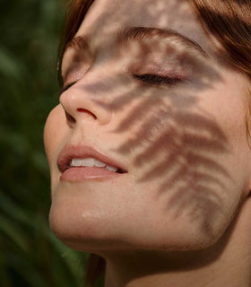 Close-up of a woman's face with sunlight casting shadows on her skin.