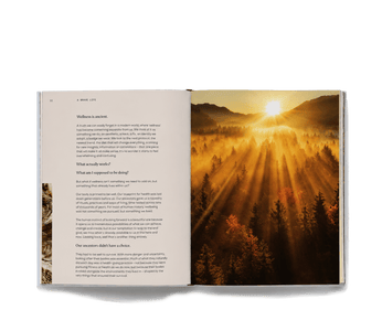 An open copy of A Brave Life featuring text about wellness rituals on the left and a landscape photo of a forest at sunrise on the right.