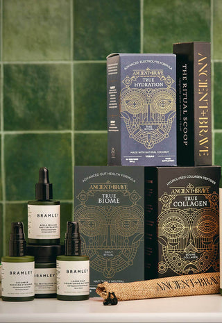 Bathroom setting with skincare products and books against a green tiled wall.