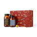 Two glass jars of collagen peptides and electrolyte powder with a gold-colored measuring scoop positioned in front of an Ancient + Brave Rise Gift Set red box decorated with gold botanical illustrations.