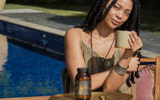 Woman holding a cup by a poolside with a bottle of Ancient + Brave's True Collagen and tray on a table