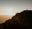 Silhouette of a person on a rocky outcrop against a sunset sky.