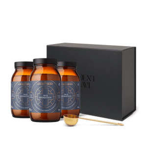 3 amber glass jars of True Hydration with a black gift box in the background, and a gold ritual scoop from Ancient and Brave