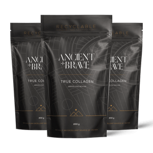 Three stand-up pouches of Ancient + Brave's True Collagen powder arranged in a fan shape against a solid black background. The packaging is dark grey with white text and gold accents.