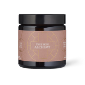 A dark amber glass jar with a black lid and a dusty rose label featuring gold geometric line art and the text 'TRUE SKIN ALCHEMY'.