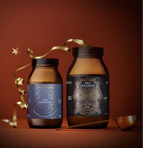 An Ancient + Brave Rise Gift Set consisting of two brown glass supplement jars of electrolyte powder and collagen peptides, decorated with a gold ribbon and a small star ornament.