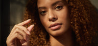 Female with curly brown hair hair holding an Ancient + Brave True Omegas soft gel