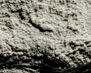 A close-up texture shot of coarse white salt crystals with deep black shadows highlighting their granular structure.